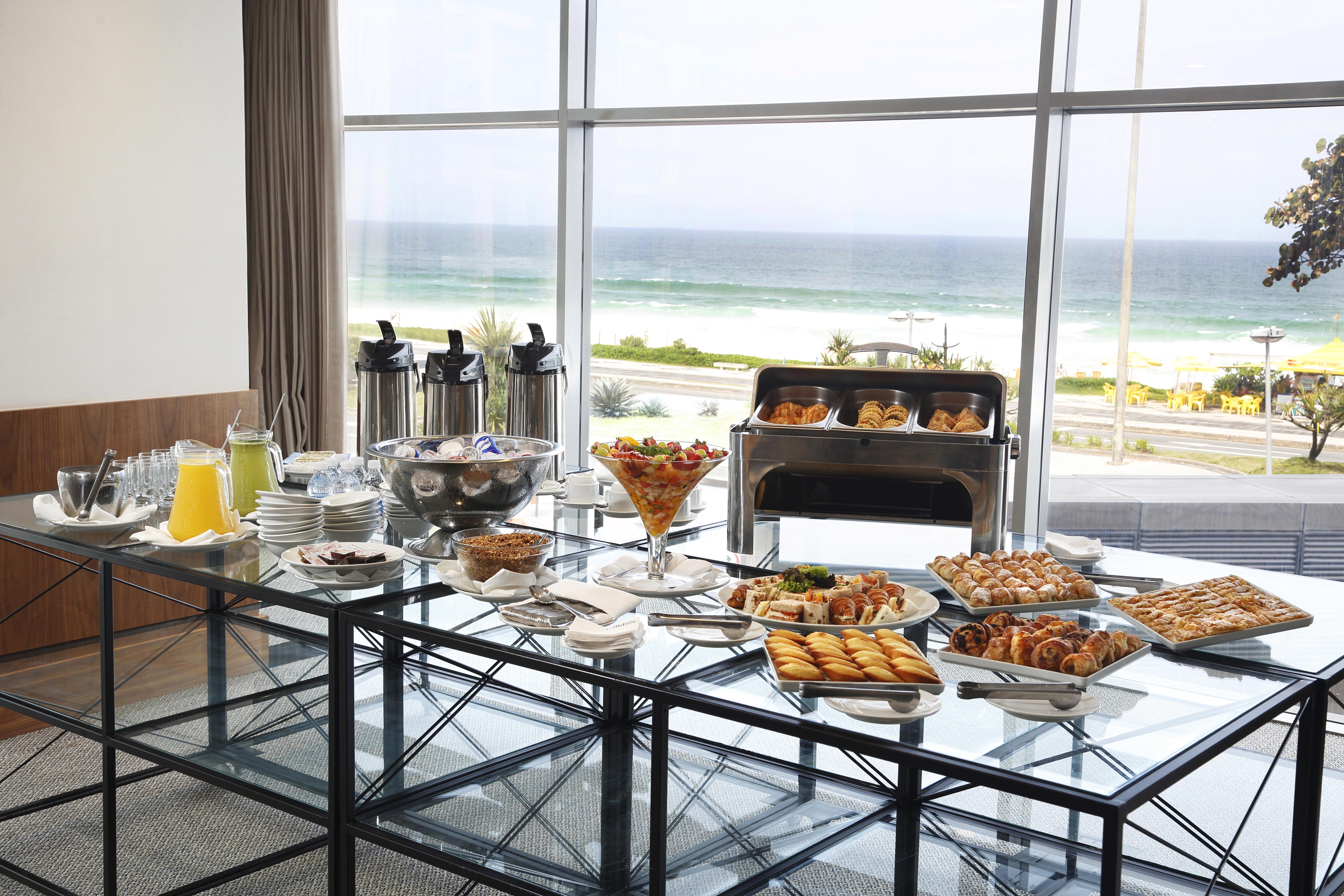 ホテル ウィンザー マラペンディ リオデジャネイロ エクステリア 写真 The photo shows a beautifully arranged buffet table with a variety of food items. In the foreground, there are multiple plates and bowls filled with different dishes, including pastries, fruits, and savory items. There are also drinks available, such